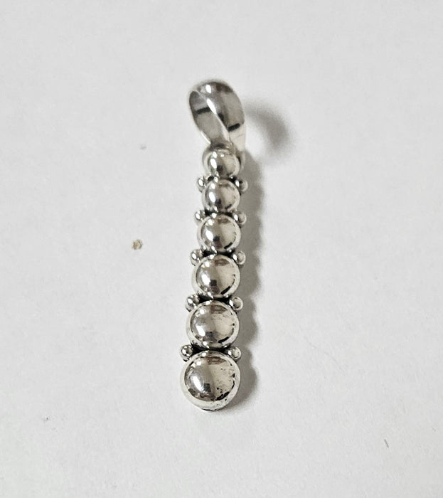 Silver pendant with five spherical beads on a white background
