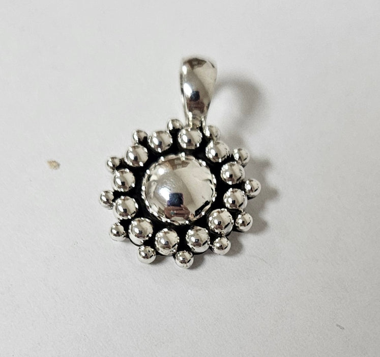 Silver pendant with a central round stone on a light gray background